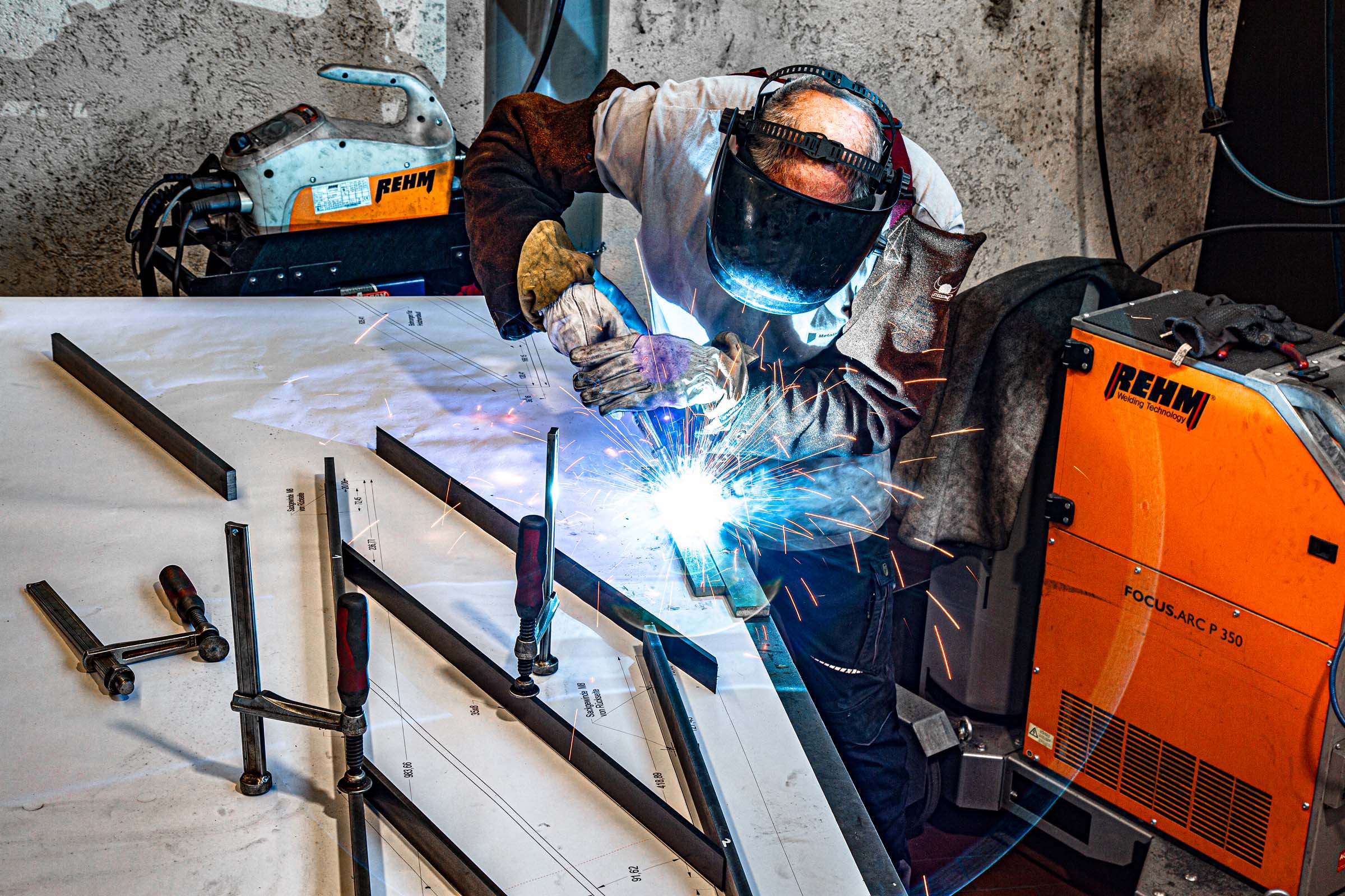 Handschweißen auf Schweißplan bei Krieger-Treppen Mitarbeiter beim Handschweißen von Metallprofilen nach exaktem Plan in der Schlosserei
